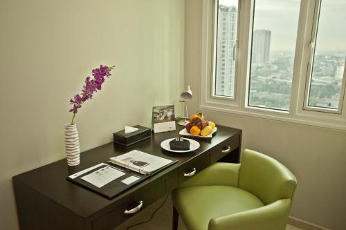 a desk with a green chair and a vase of flowers at The Exchange Regency Residence Hotel Managed by HII in Manila