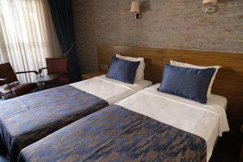 two beds in a hotel room with blue pillows at Azka Hotel in Bodrum City