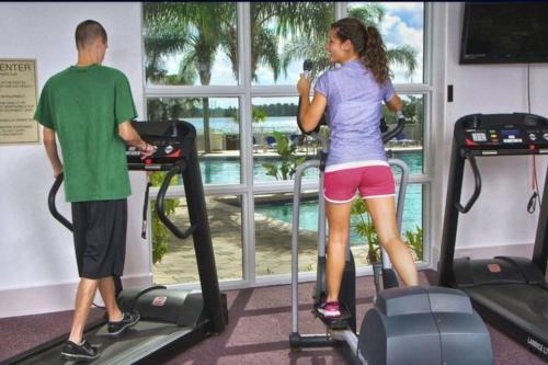 a man and a woman on treadmills in a gym at Lake view condo close to Disney in Orlando
