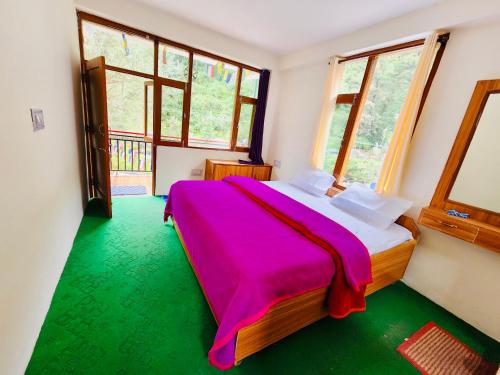 a bedroom with a bed with a pink blanket at Hostel 360 Degree in Manāli