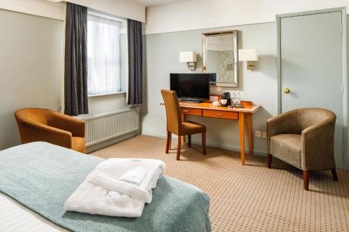 a hotel room with a bed and a desk with a computer at Mercure Bolton Georgian House Hotel in Bolton