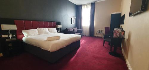 a hotel room with a large bed and a chair at The John Francis Basset Wetherspoon in Camborne