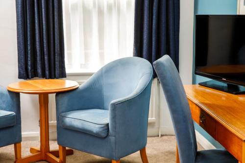 a living room with a blue chair and a table at Mercure Bolton Georgian House Hotel in Bolton