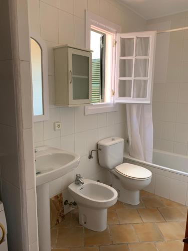 a white bathroom with a toilet and a sink at Apartamento en frente de la playa in Son Parc