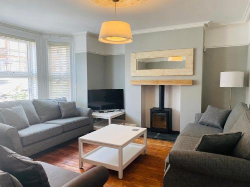 a living room with a couch and a fire place at Coast House Cromer - Sleeps 15, hot tub, sea views in Cromer