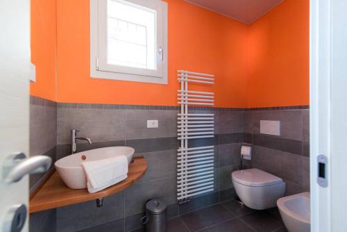 トルノにあるAppartamento Persico - Lake view and private parkingのオレンジ色のバスルーム(洗面台、トイレ付)