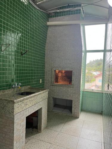 a green tiled bathroom with a fireplace and a sink at La Lola Residencial in Bombinhas