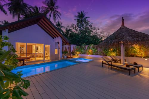 une villa avec une piscine la nuit dans l'établissement Malahini Kuda Bandos Resort, à Atoll Malé Nord