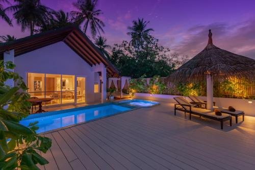 Villa con piscina por la noche en Malahini Kuda Bandos Resort, en Atolón de Malé Norte