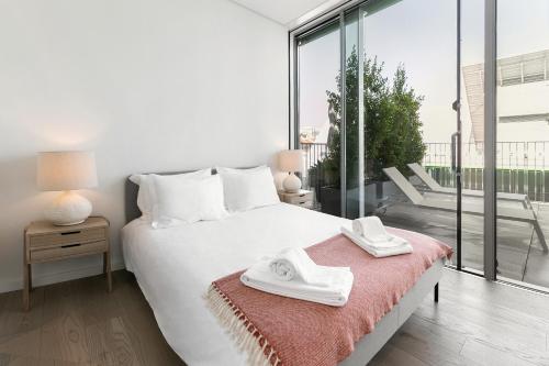 a bedroom with a white bed and a large window at Prata Riverside Apartment in Lisbon