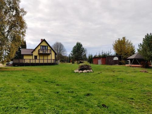 a yellow house in a field of green grass at Ilvese Cottage Lintsi jõe kaldal in Änari
