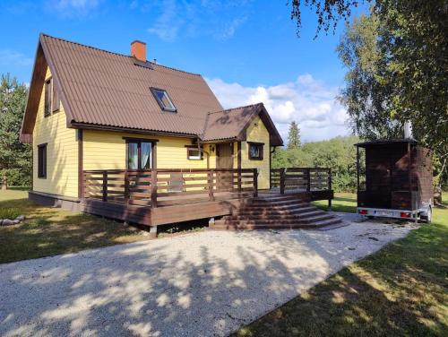 a small yellow house with a wooden porch and stairs at Ilvese Cottage Lintsi jõe kaldal in Änari