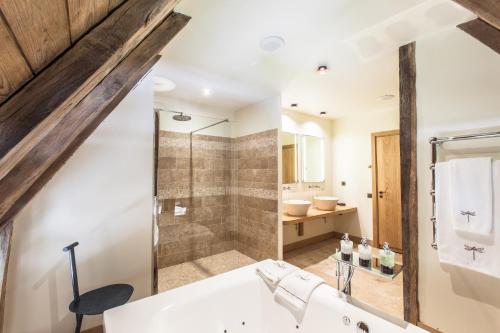a bathroom with a shower and a white tub at HOTEL Domaine des Etangs, Auberges Resorts Collection in Massignac