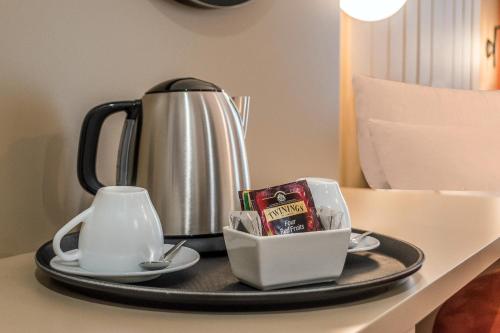 a tray with a tea kettle and a packet of candy at BB Hotels Smarthotel Duomo in Milan