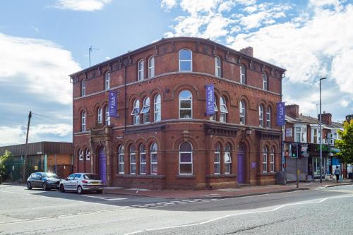 ein großes rotes Backsteingebäude mit blauen Schildern darauf in der Unterkunft Pillo Rooms Serviced Apartments - Salford in Manchester