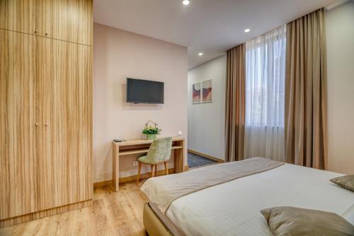 a bedroom with a bed and a desk and a television at Orbeli Hotel Yerevan in Yerevan
