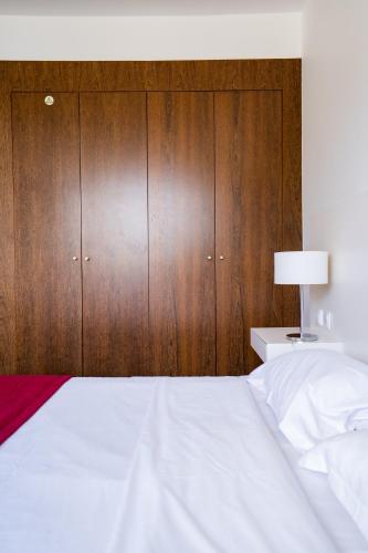 a bedroom with a white bed and wooden cabinets at Hotel Vila D'Óbidos in Óbidos