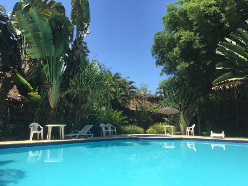 a swimming pool with two chairs and a table and chairs at Casa sossegada ao lado da natureza e do mar in São Sebastião