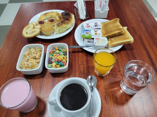 Hotel AATRAC Buenos Aires في بوينس آيرس: طاولة مع أطباق من طعام الإفطار وكوب من القهوة