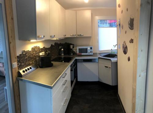 a kitchen with white cabinets and a counter top at Ferienhaus Zeulenrodaer Meer in Stelzendorf