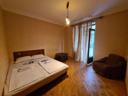 a bedroom with a bed and a chair and a window at Benevo Hostel in Tbilisi City