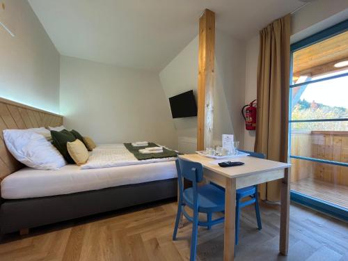 - une chambre avec un lit, une table, un lit et une fenêtre dans l'établissement Hotel Edvard, à Frenštát pod Radhoštěm