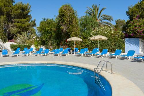 una piscina con sedie a sdraio e ombrelloni blu di Hotel Apartamentos Vibra Monterrey a Baia di Sant'Antoni