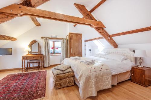 a bedroom with a bed and a table and a mirror at Thatch Close Cottages in Ross on Wye