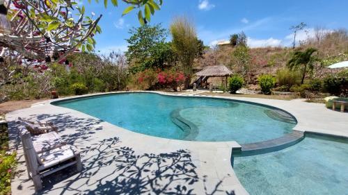 a large swimming pool in a yard with a patio at Lombok Villas, Villa KuraKura in Labuhanpoh