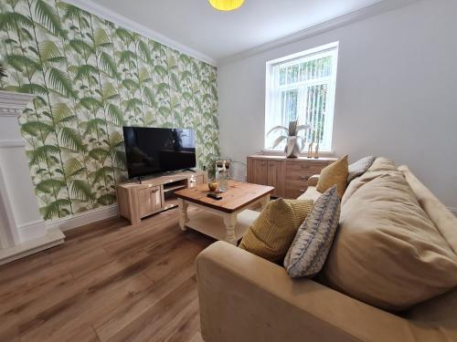 a living room with a couch and a tv at Beautiful 4 bedroom house near town centre. With Bike Store Perfect for Bike Park Wales in Merthyr Tydfil