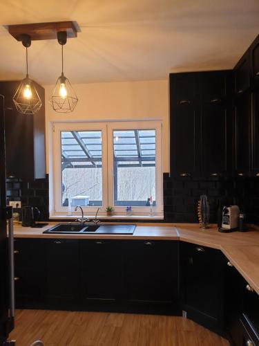 eine Küche mit schwarzen Schränken, einem Waschbecken und einem Fenster in der Unterkunft Flow House in Satu Mare