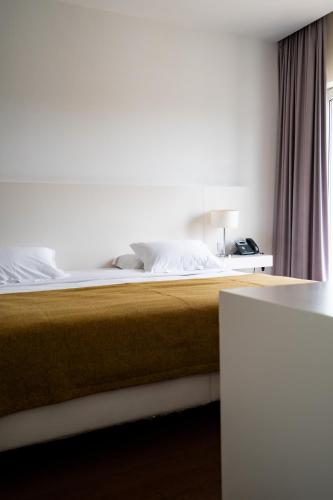 a bed in a hotel room with a bedskirtspectspectssenalsenalsenalsenal at Hotel Vila D'Óbidos in Óbidos