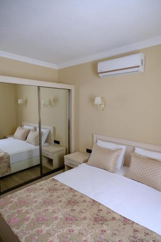 a bedroom with two beds and a mirror at Azka Hotel in Bodrum City