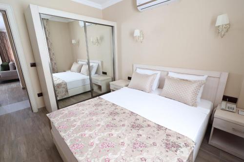 a bedroom with a large white bed and a mirror at Azka Hotel in Bodrum City