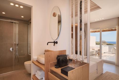 a bathroom with a shower and a toilet and a mirror at Armony Suites Milos in Paliochori