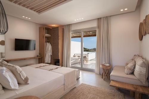 1 dormitorio con cama, TV y balcón en Armony Suites Milos, en Paliochori
