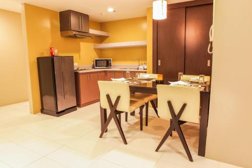 a kitchen with a table and chairs and a refrigerator at The Exchange Regency Residence Hotel Managed by HII in Manila
