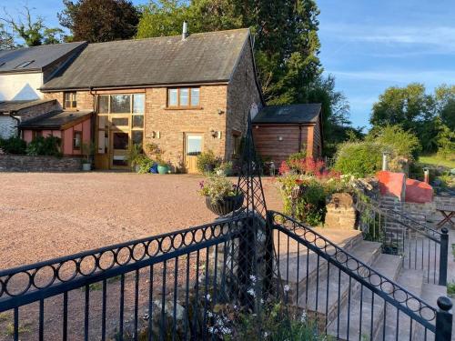 a brick house with a fence in front of it at Thatch Close Cottages in Ross on Wye