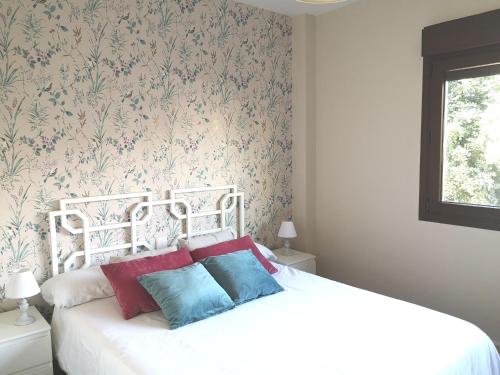 マラガにあるEspectacular Apartamento Malaga Playa Y Piscinaの花柄の壁紙を用いた白いベッドが備わるベッドルーム1室