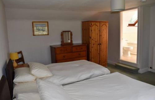 a bedroom with two beds and a dresser and a window at Craignuisq Farmhouse in Pitlochry