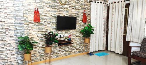 a room with a brick wall with a tv and plants at The Homeland Stay in Ahmedabad