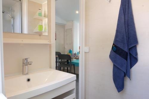 baño con lavabo y toalla azul en Happy Camp mobile homes in Villaggio Camping Baia Domizia, en Baia Domizia