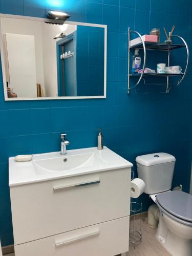 La salle de bains bleue est pourvue d'un lavabo et de toilettes. dans l'établissement La Chambre du Patio, au Luc