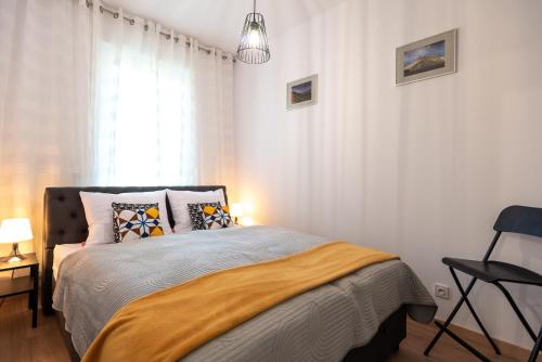 a bedroom with a bed and a chair next to a window at Apartament LUX 3 Cieplice in Jelenia Góra