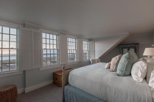 um quarto com uma cama com janelas em The Wauwinet Nantucket em Wauwinet