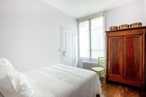 a bedroom with a bed and a wooden cabinet at Le Monarque - Appartement avec jardin in Chaville
