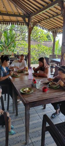 a group of people sitting around a wooden table at D'kailash Retreat in Singaraja
