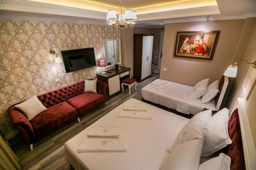 a hotel room with a bed and a couch and a tv at Legacy Boutique Hotel in Korçë