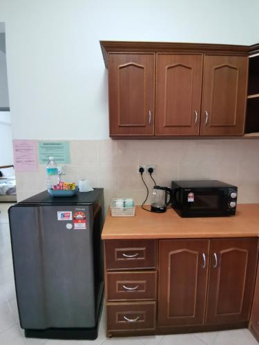a kitchen with a black refrigerator and wooden cabinets at My Getaway Home @Marina Cove in Lumut