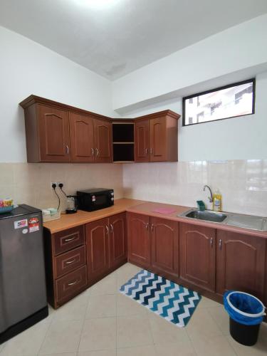a kitchen with wooden cabinets and a stainless steel refrigerator at My Getaway Home @Marina Cove in Lumut